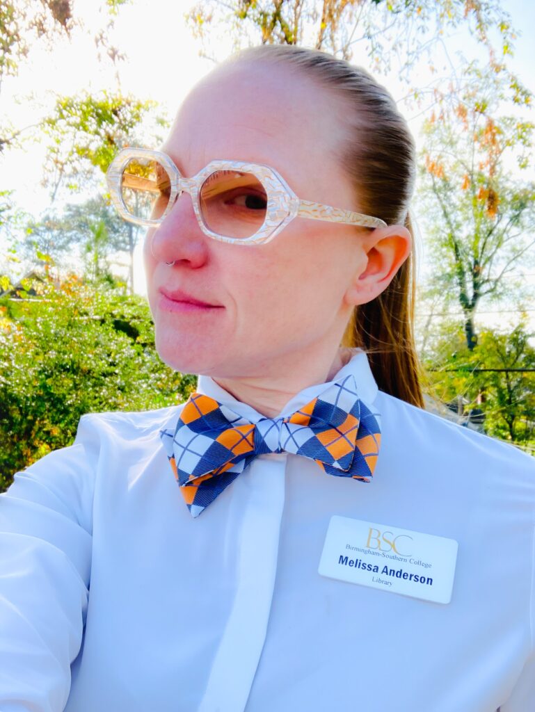 Melissa Anderson wearing sunglasses and white shirt with a bowtie